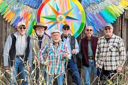 Photo of six artist standing in front of artwork on an old barn
