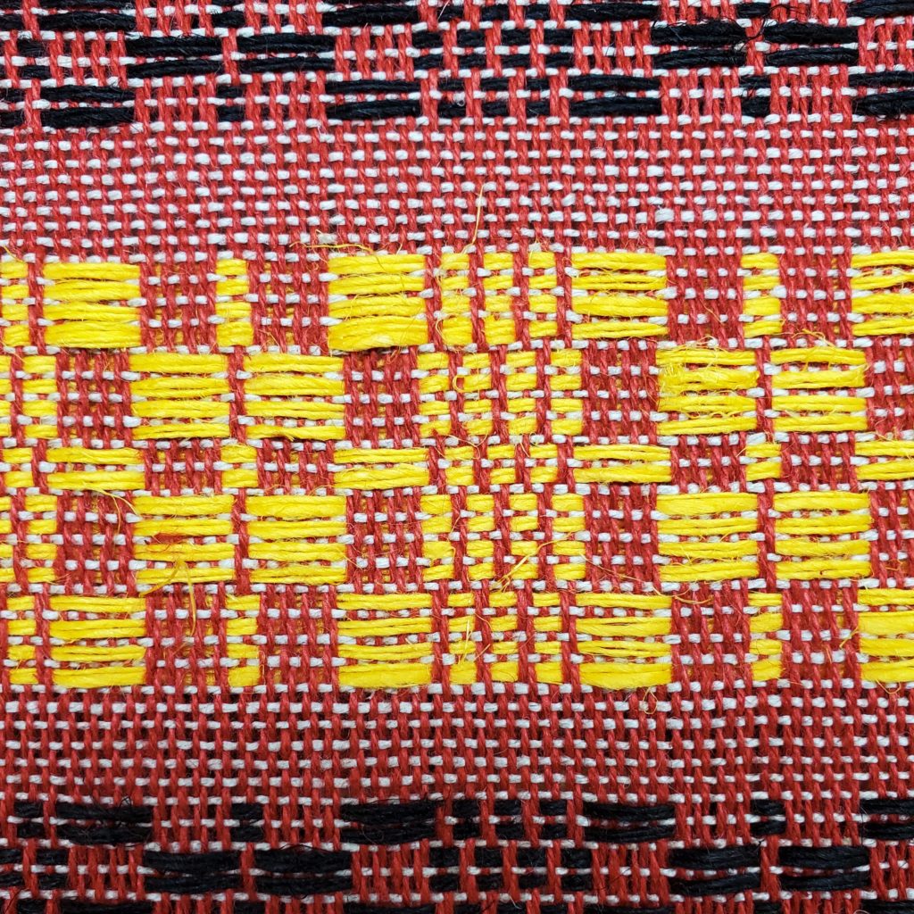 Image of a woven textile piece with red, yellow and black threads
