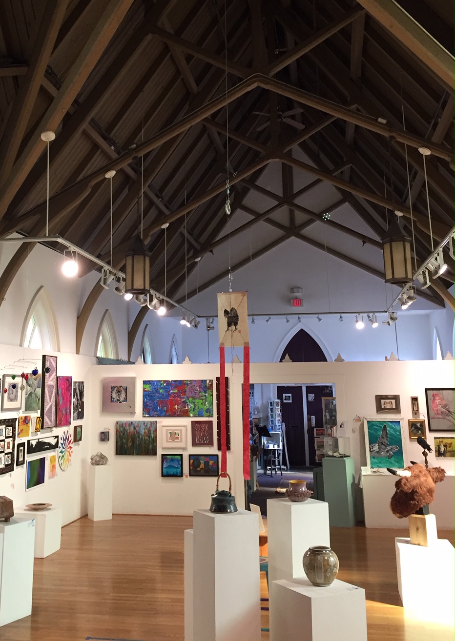 photo of tall gothic ceilinged room full of artwork covering all of the walls.