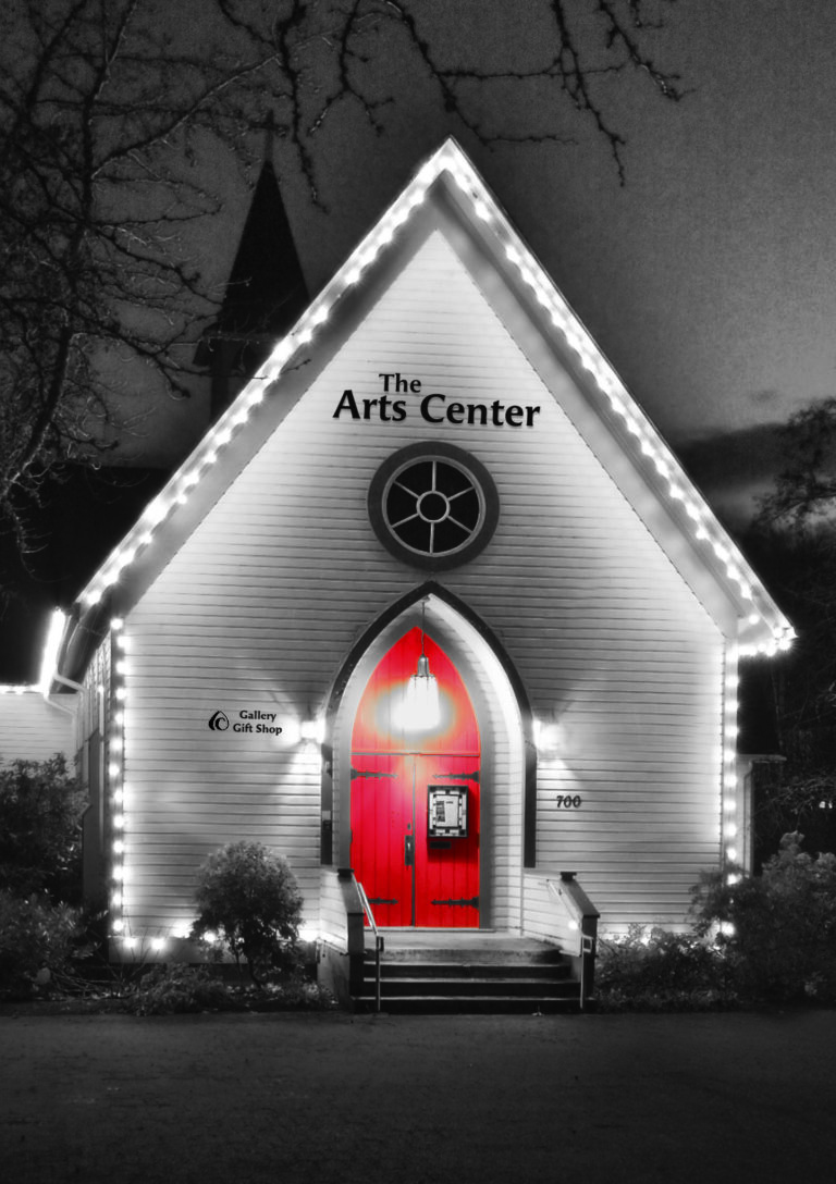 The Arts Center Building as black and white image with holiday lights glowing and the front entrance door in color being a prominent Red-colored element.