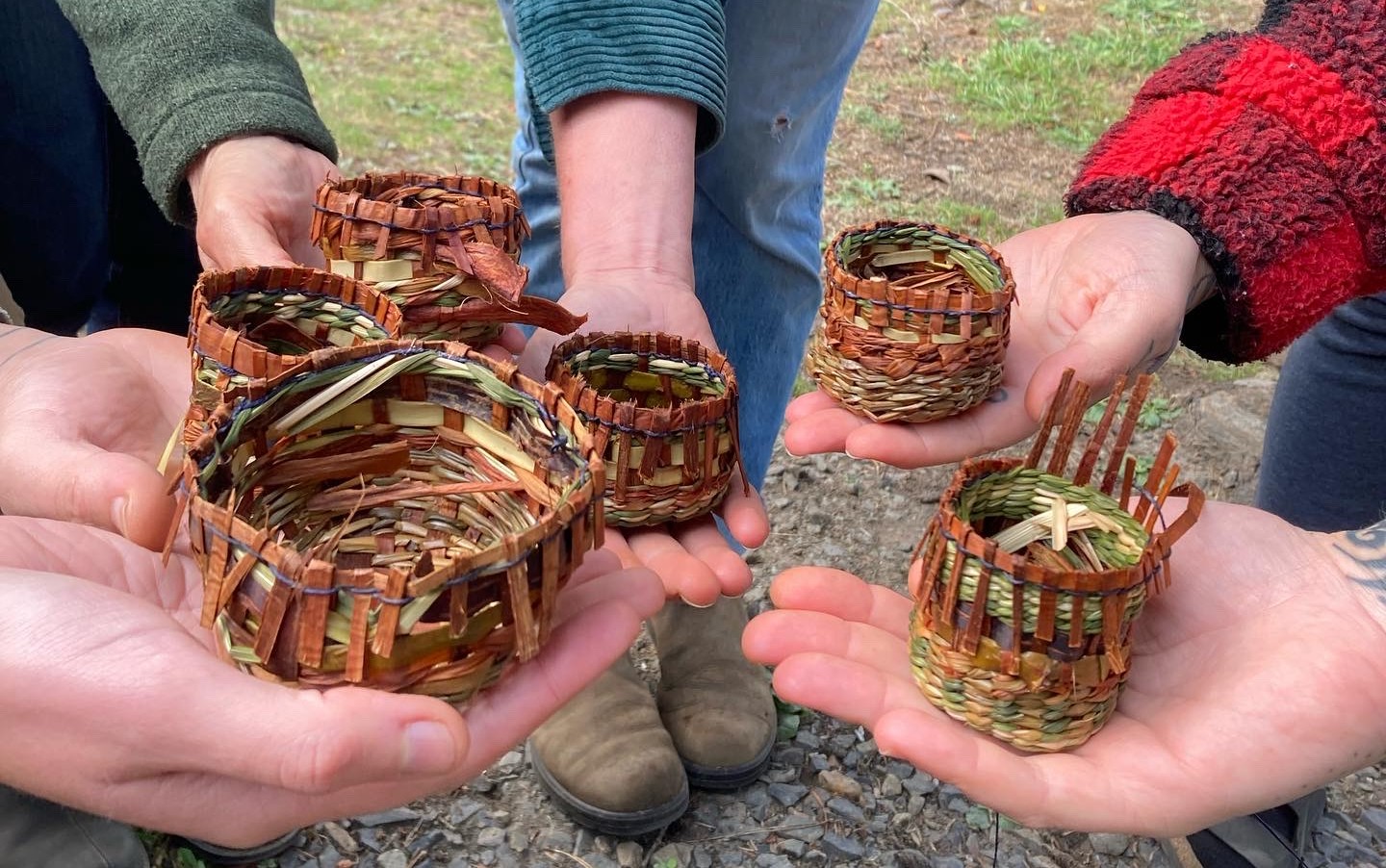 Six hands holding small bark baskets